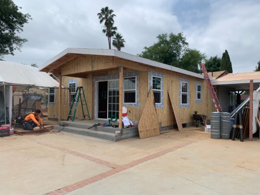 Newly constructed house with wooden framing, steps, and construction tools nearby.