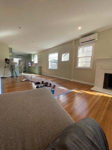 Bright, spacious living room with hardwood floors and a fireplace, partially under renovation.