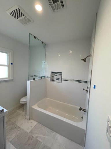 Bright, modern bathroom featuring a glass-enclosed shower and a white bathtub.