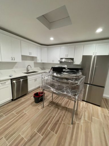 Modern kitchen with stainless steel appliances and a table covered in plastic wrap.
